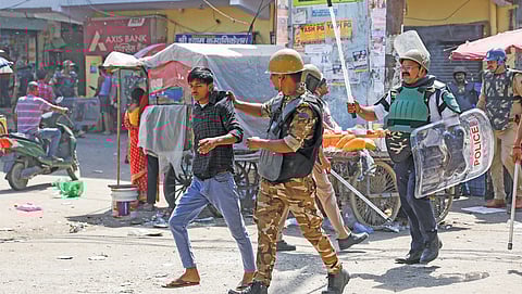 Police detain a man in Noida, Uttar Pradesh, on April 14 while patrolling a neighbourhood after protests by factory workers for higher wages
