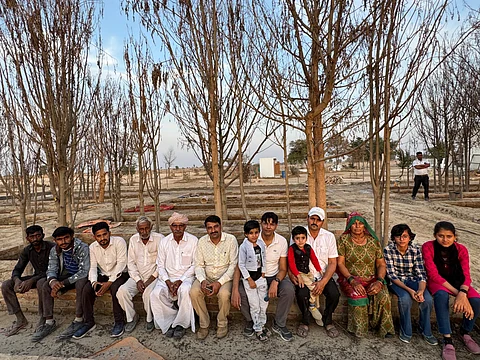 श्याम सुंदर ज्याणी (बीच में दो बच्चों के साथ बैठे हुए) राजस्थान के बीकानेर जिले के उत्तमदेसर गांव के निवासियों के साथ। फोटो: माधव शर्मा