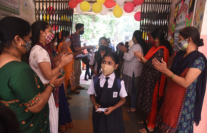 पहिल्या दिवशी विद्यार्थ्याचे स्वागत करताना शिक्षक (छायाचित्रे विजय बाटे )