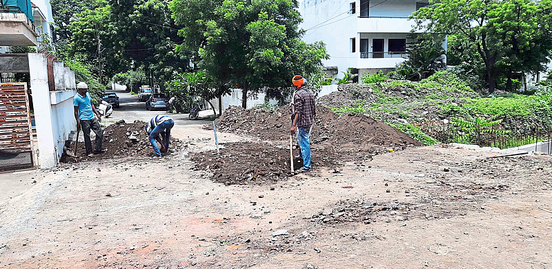 Workers filling a ditch beside a drain in Jayanagar.