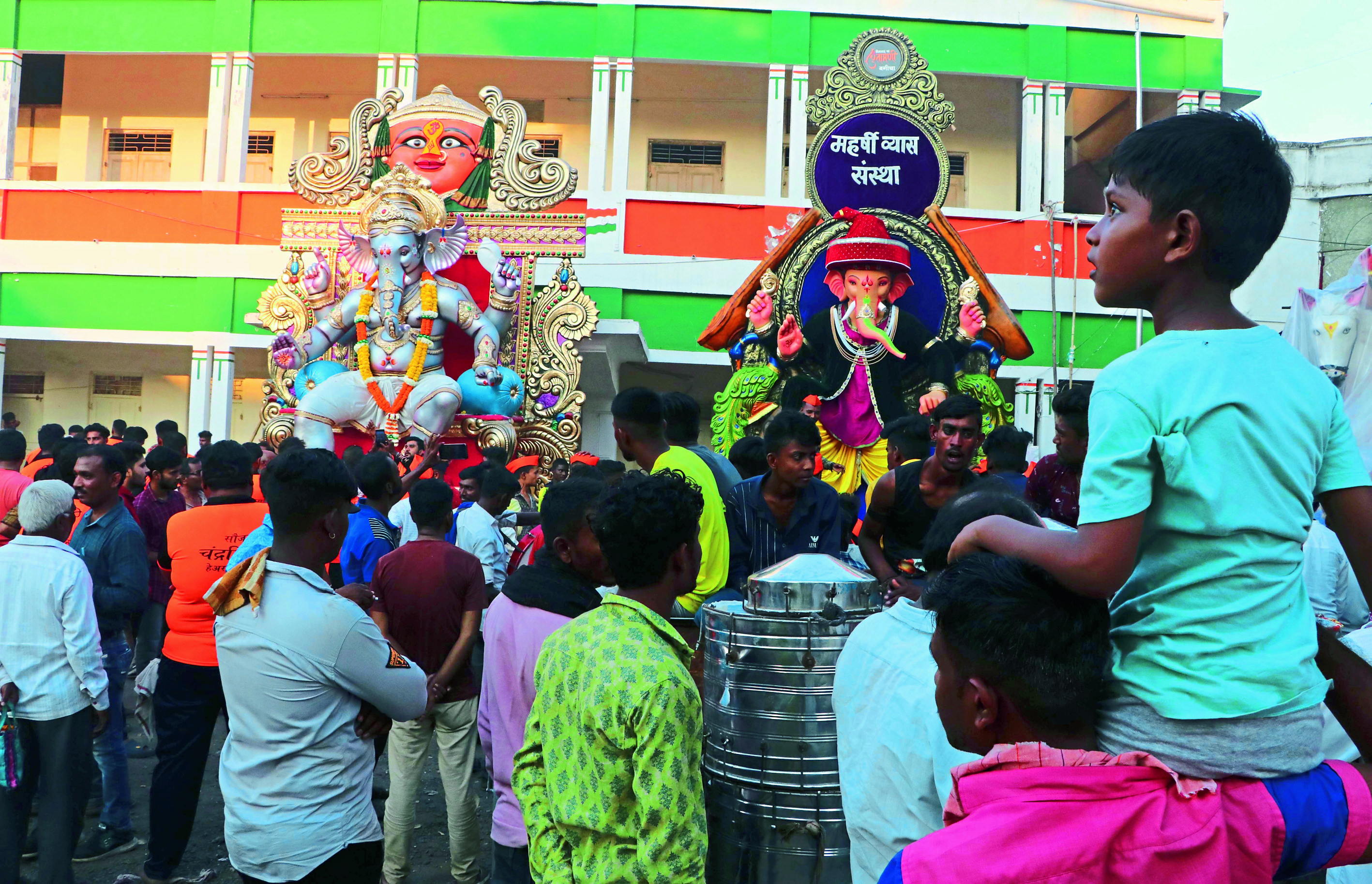 आपल्या मुलाला खांद्यावर घेऊन गणपती बाप्पाचे दर्शन करविताना पालक