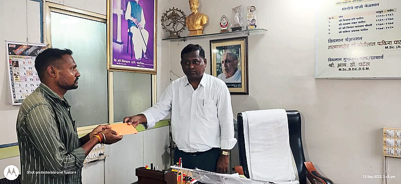 Principal I D. Patel. while handing over financial aid for child's education to Ritesh Dodve.