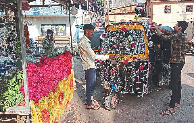 A flower seller and a rickshaw puller decorating a rickshaw on the occasion of Lakshmi Pujan