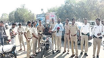 Motor vehicle inspector giving flowers to drivers wearing helmets by Regional Transport Department here.