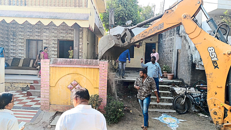 A team of JCB demolishing the wall compound of a house on encroached land in Sakri Road area