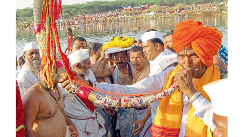 नीरा (ता. इंदापूर) - नीरास्नान आटोपल्यानंतर डोक्यावर पादुका घेऊन जाताना सोहळाप्रमुख.