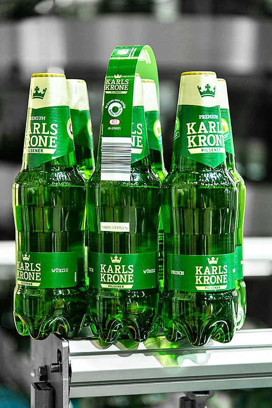 The material-saving Nature MultiPack system from KHS forms cans or PET bottles into stable packs with the help of small dots of adhesive. Martens and KHS have produced film-free six-packs of PET bottles for the retail trade.