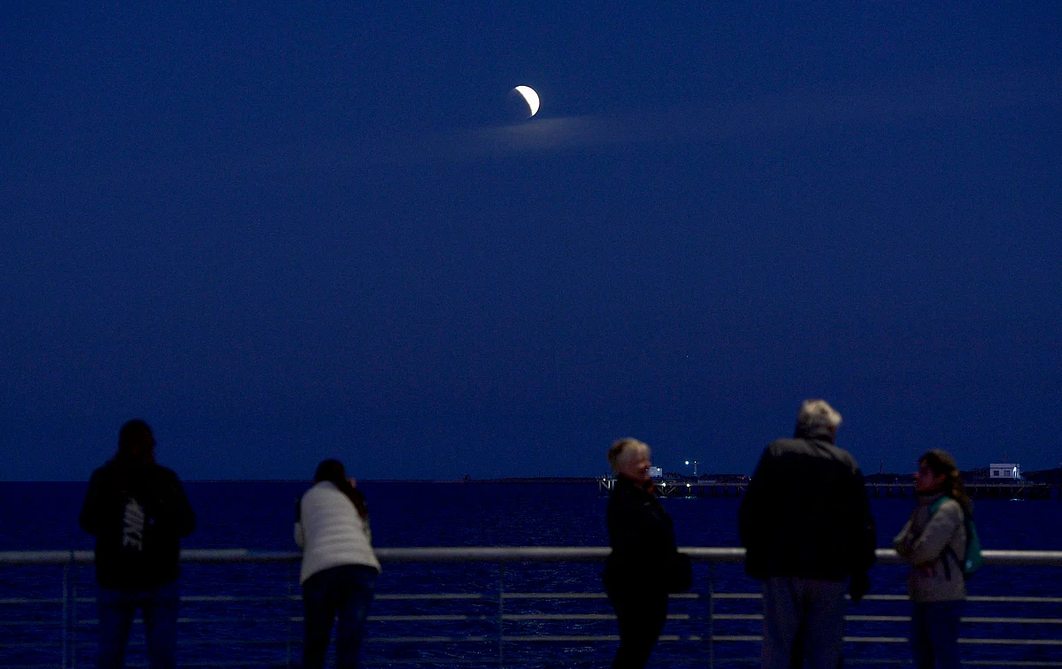 People watch the moon during a partial eclipse on the shore of the Rio de la Plata river in Buenos Aires on July 16, 2019.