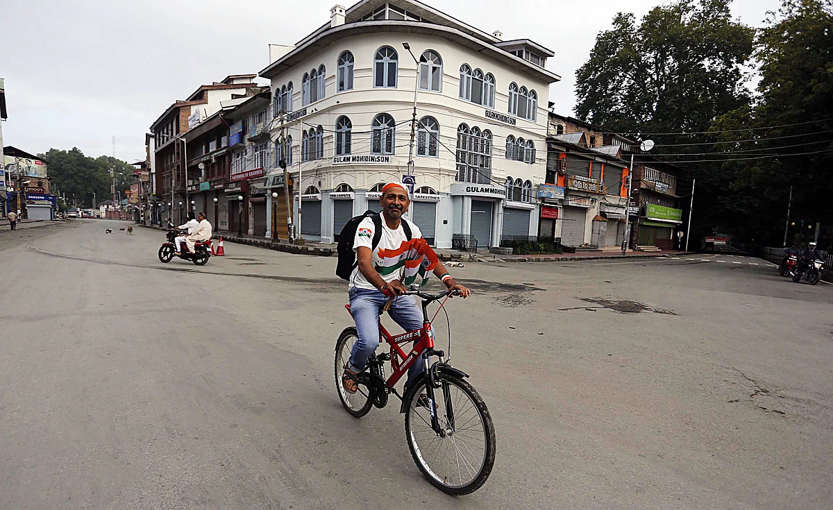 A man rides a bicycle with National flags during the 73rd Independence Day celebration in Srinagar
