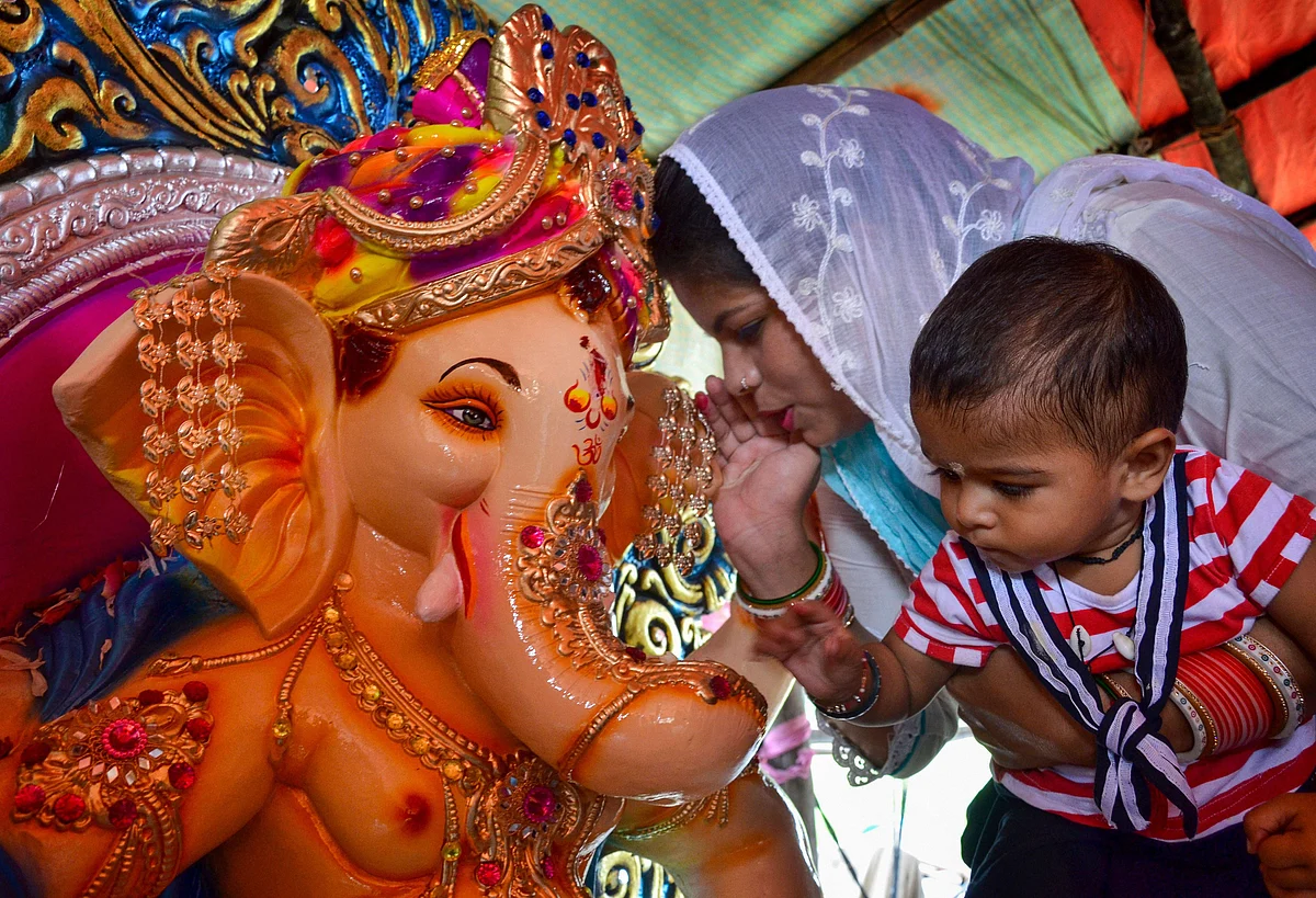 A devotee whispers a wish in the ear of an idol of Hindu God Ganesha as part of a ritual on the occasion of Ganesha Chaturthi, in Amritsar