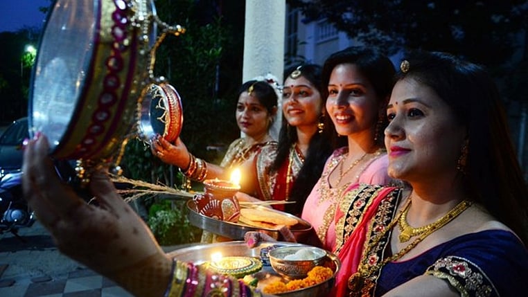 Women watch the moon through a sieve before breaking fast on Karva Chauth