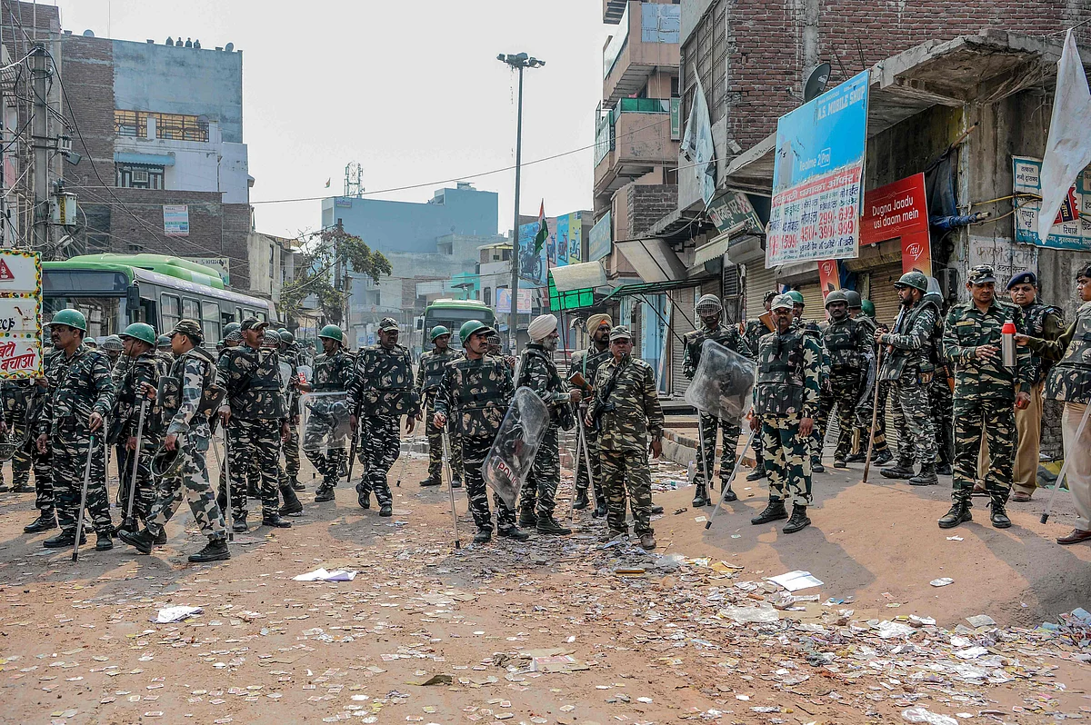 Security personnel stand guard near burnt-out and damaged shops following clashes between people supporting and opposing a contentious amendment to India's citizenship law, in New Delhi on February 26, 2020.