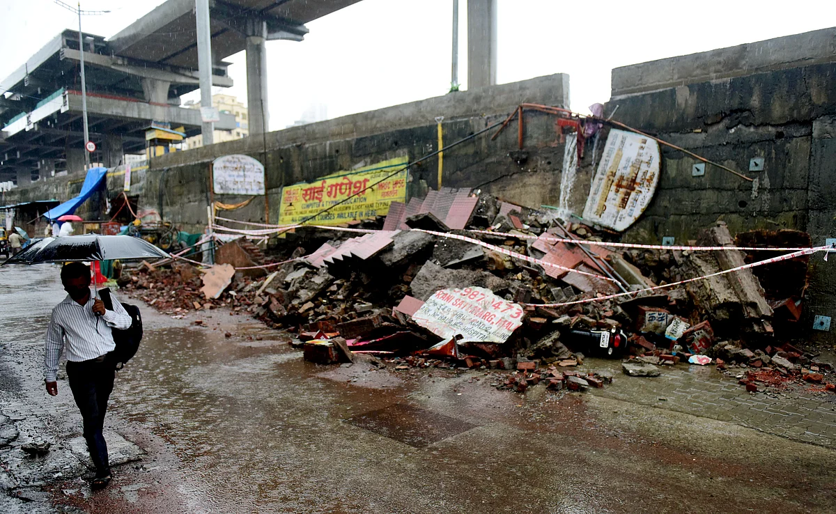 A man holds an umbrella walk past collapsed Joint Walking bridge due to rainfall, at Pushpa Park Malada East in Mumbai on Sunday