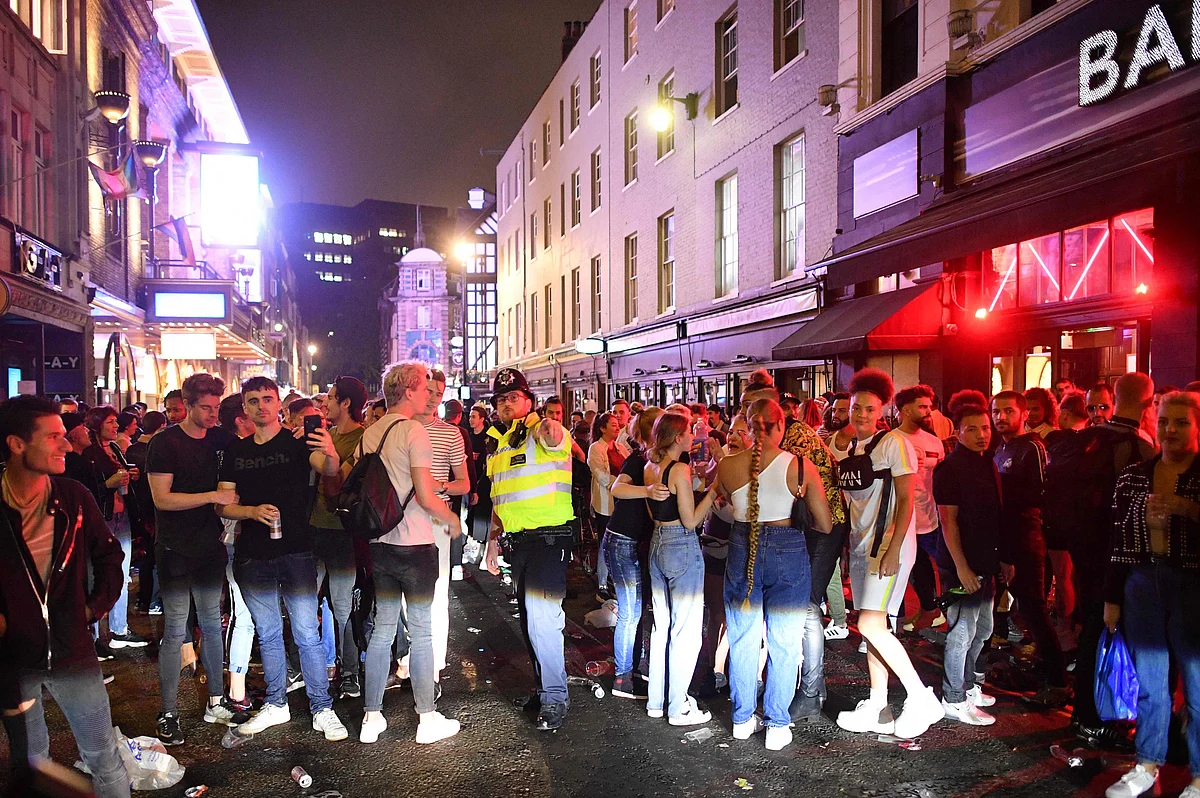A police officer tries to tell revellers filling the street outside bars in the Soho area of London on July 4, 2020, that the road has been reopened to car traffic as restrictions are further eased during the novel coronavirus COVID-19 pandemic.