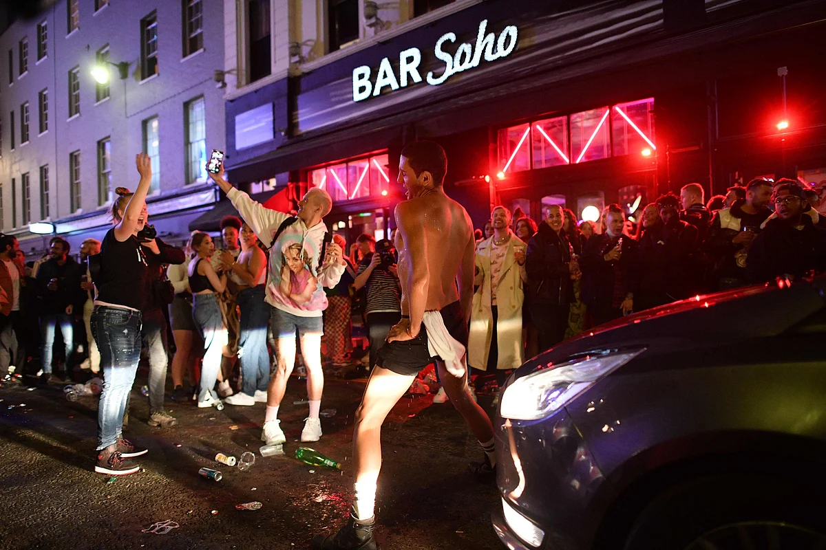 A car tries to drive along a street filled with revellers drinking in the Soho area of London on July 4, 2020, after the police re-opened the road at 2300 as restrictions are further eased during the novel coronavirus COVID-19 pandemic.