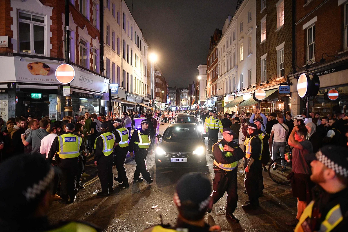 Police officers move revellers from the road to allow traffic to pass in the Soho area of London on July 4, 2020, after the police re-opened the road at 2300 following a further easing of restrictions to allow pubs and restaurants to open during the novel coronavirus COVID-19 pandemic.