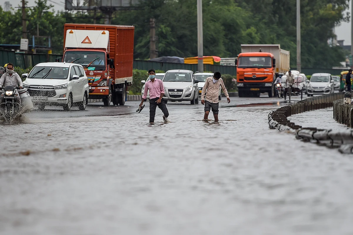 Vehicles and people wade on a flooded road following monsoon rainfall in Gurugram on August 20, 2020.
