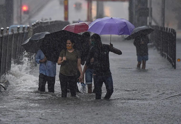 Pedestrians cross a waterlogged street during heavy rains, at Sion in Mumbai, Wednesday, Aug. 5