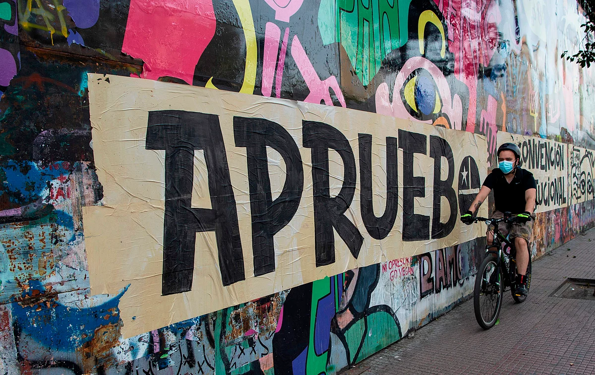 A man rides his bicycle past a graffiti referring to the October 25 referendum to decide whether to change the constitution established under the military rule of General Augusto Pinochet (1973-90), during a rally in support of the amendment, in Santiago, on October 17, 2020. - Changing the constitution enacted under former dictator Augusto Pinochet, who ruled from 1973-90, was a key demand of protesters during the two months of violent civil unrest against the government and inequality. Chileans will be asked two questions on October 25: do they want a new constitution and who should draft it.