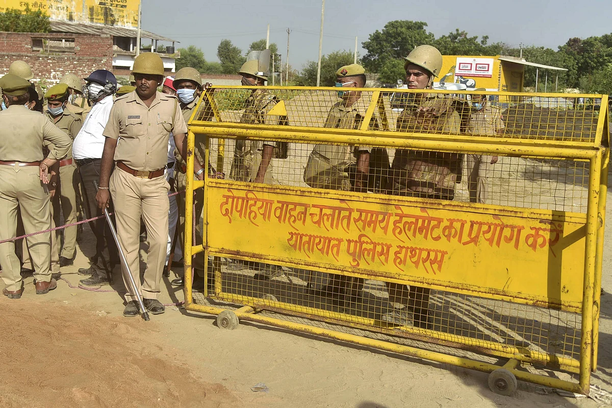 Police personnel stand guard near a on a road leading to Bulgari village, following the death of a 19-year-old Dalit woman after an alleged gangrape, in Hathras district, Saturday, Oct. 3, 2020