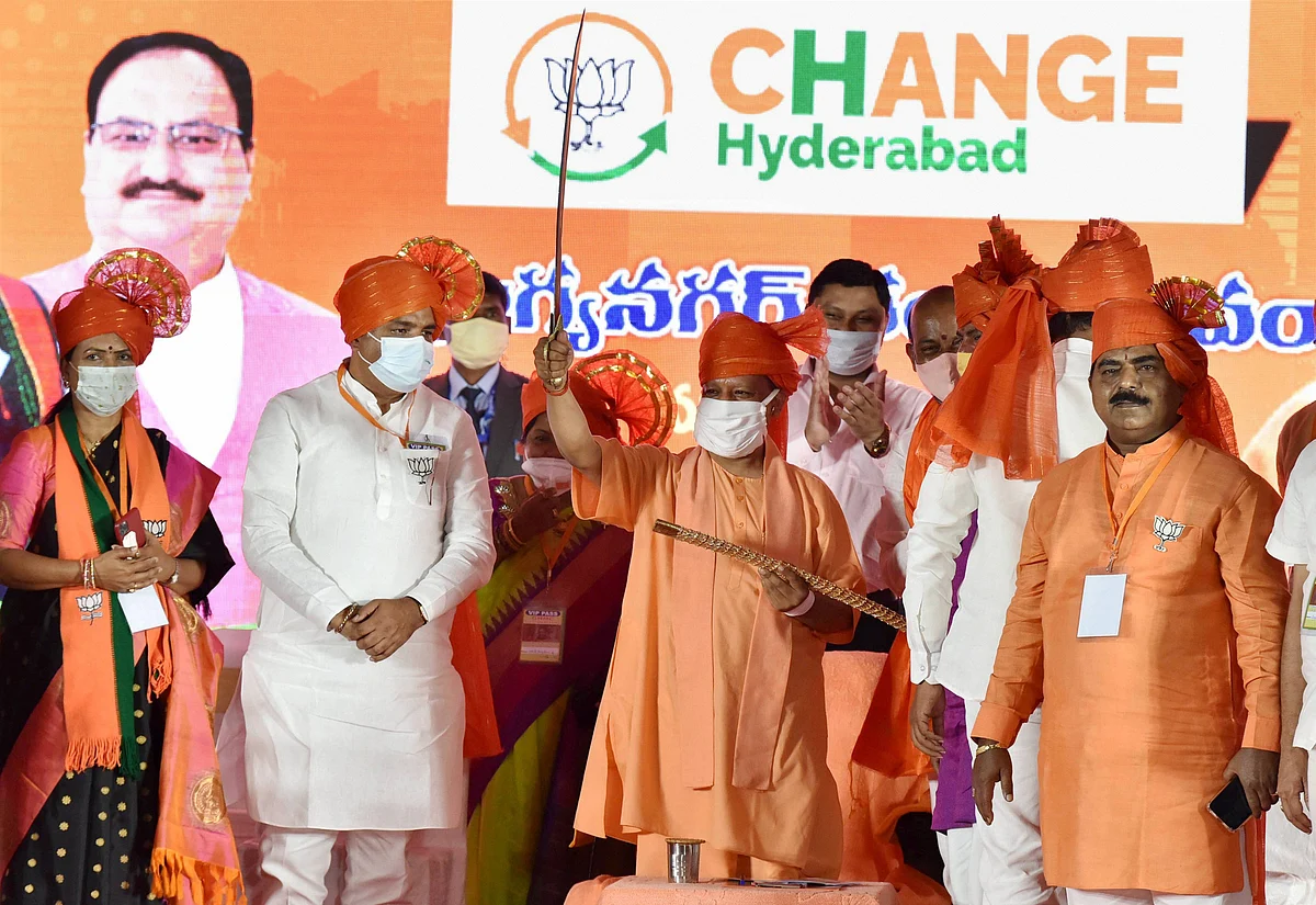 Uttar Pradesh Chief Minister Yogi Adityanath, flanked by BJP Telangana leaders, holds a sword during a public meeting, ahead of GHMC elections in Hyderabad.