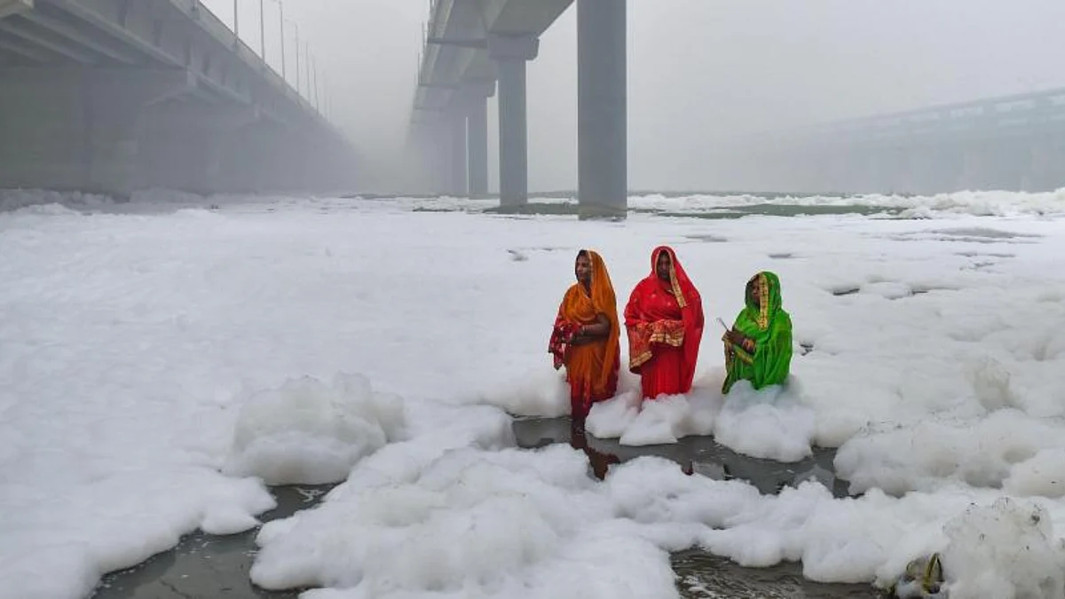 Devotees offer prayer to the rising sun as toxic 'froth' floats on the surface of a polluted Yamuna river
