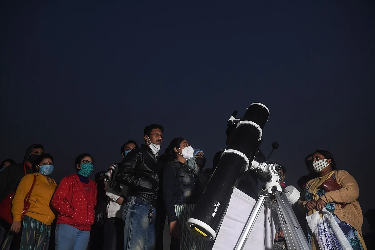 People stand in a queue to see a great conjunction of Jupiter and Saturn at the Maidan area in Kolkata on December 21, 2020.