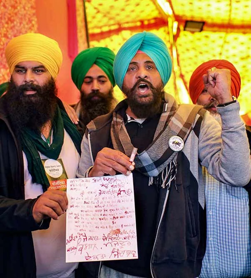 Farmers show a letter, written with their blood, to be sent to the Prime Minister during the agitation against farm reform laws, at Singhu Border in New Delhi.