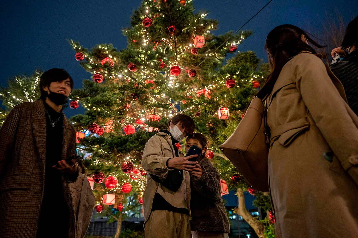 A couple takes pictures with Christmas-themed illuminated trees on Christmas eve, in Roppongi district of Tokyo