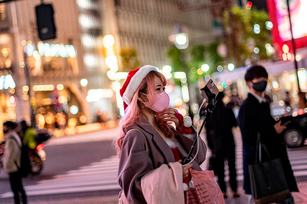 A woman wearing a Santa hat takes video clips on Christmas eve, in Shibuya district of Tokyo