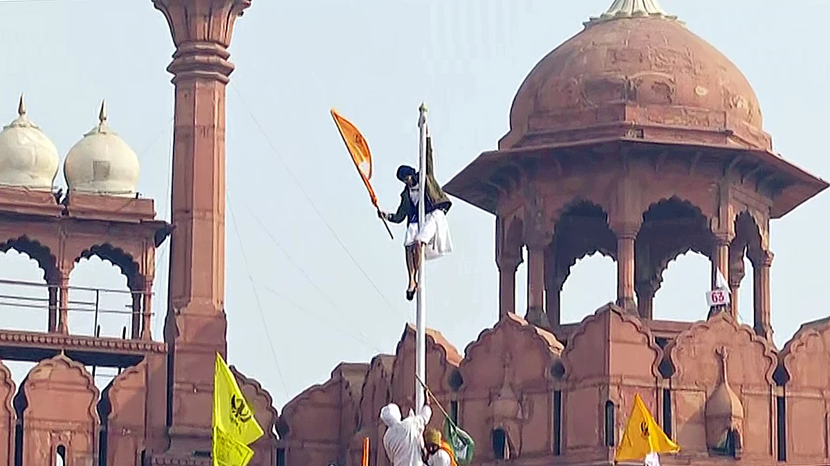 Protesting farmers hoist a flag from the ramparts of the Red Fort on 72nd Republic Day, in New Delhi on Tuesday.