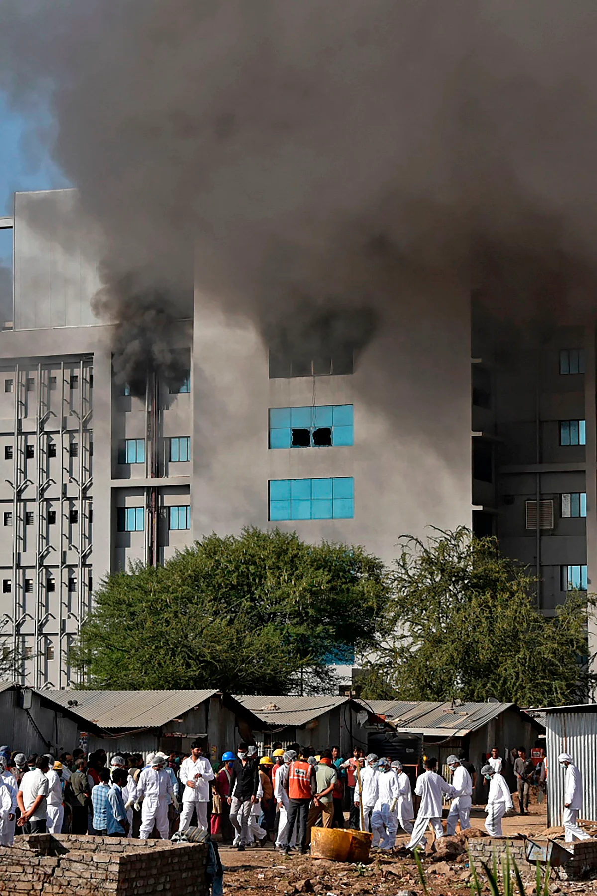 Workers wearing protective gear walk after a fire broke out at Indias Serum Institute in Pune on January 21, 2021. - A fire broke out on January 21 at Indias Serum Institute, the worlds largest maker of vaccines, but a company source said production of drugs to prevent Covid-19 coronavirus was not affected.