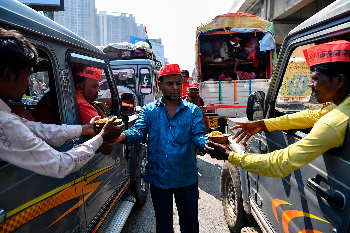 A volunteer (C) distributes food to farmers sitting in vehicles as they cross a state highway during a rally to Mumbai in support of farmers who are continuing their protest against the central governments recent agricultural reforms, at Bhiwandi in the Thane district of Maharashtra on January 24, 2021.