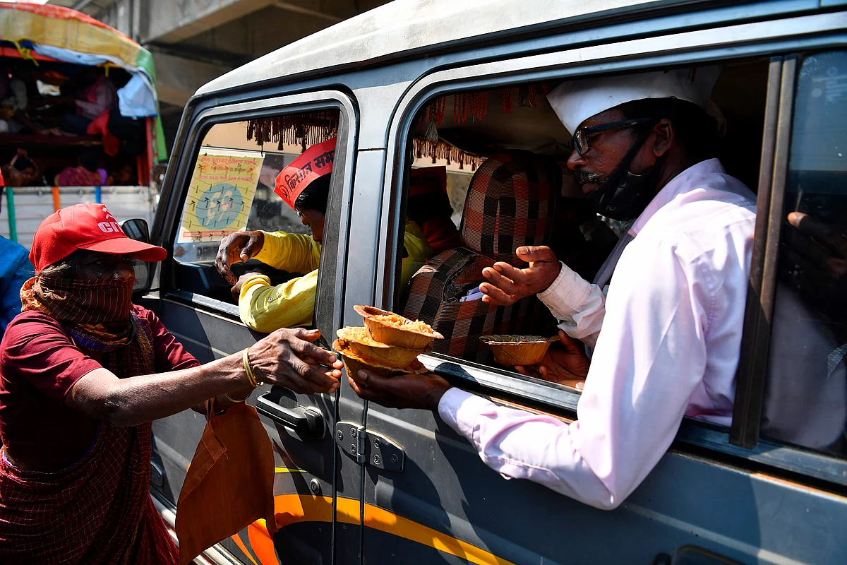 A volunteer (L) distributes food to farmers sitting in a vehicle as they cross a state highway during a rally to Mumbai in support of farmers who are continuing their protest against the central governments recent agricultural reforms, at Bhiwandi in the Thane district of Maharashtra on January 24, 2021.