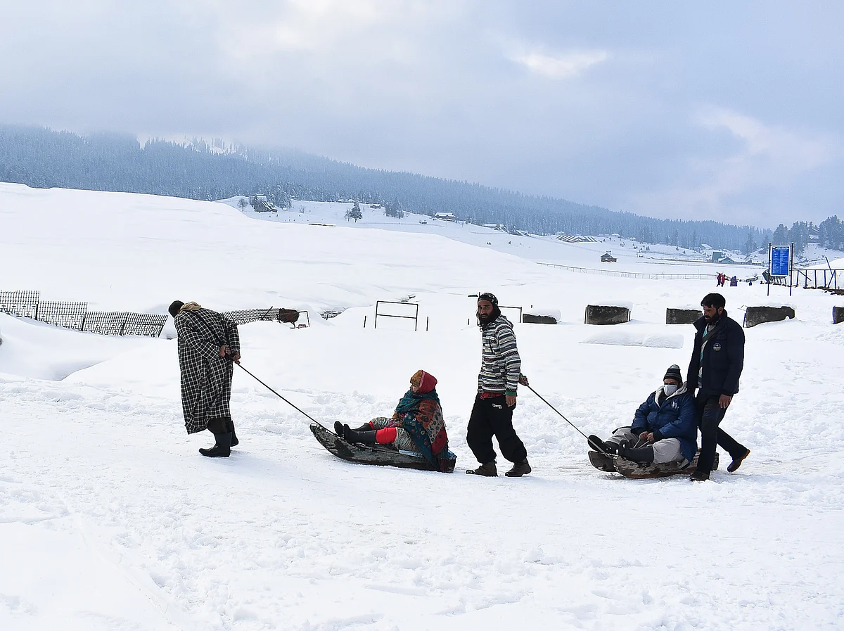Tourists enjoy the ride on snow sledges during a sunny winter day at a famous ski- resort in Gulmarg, on Tuesday.