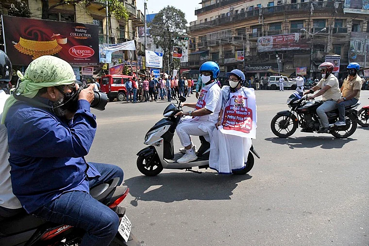 West Bengal Chief Minister Mamata Banerjee along with Mayor of Kolkata and Minister in Charge - Urban Development and Municipal Affairs Government of West Bengal Firhad Hakim protesting on the streets of Kolkata. Hakim rides the scooter while the CM sat behind sporting a slogan against the fuel price