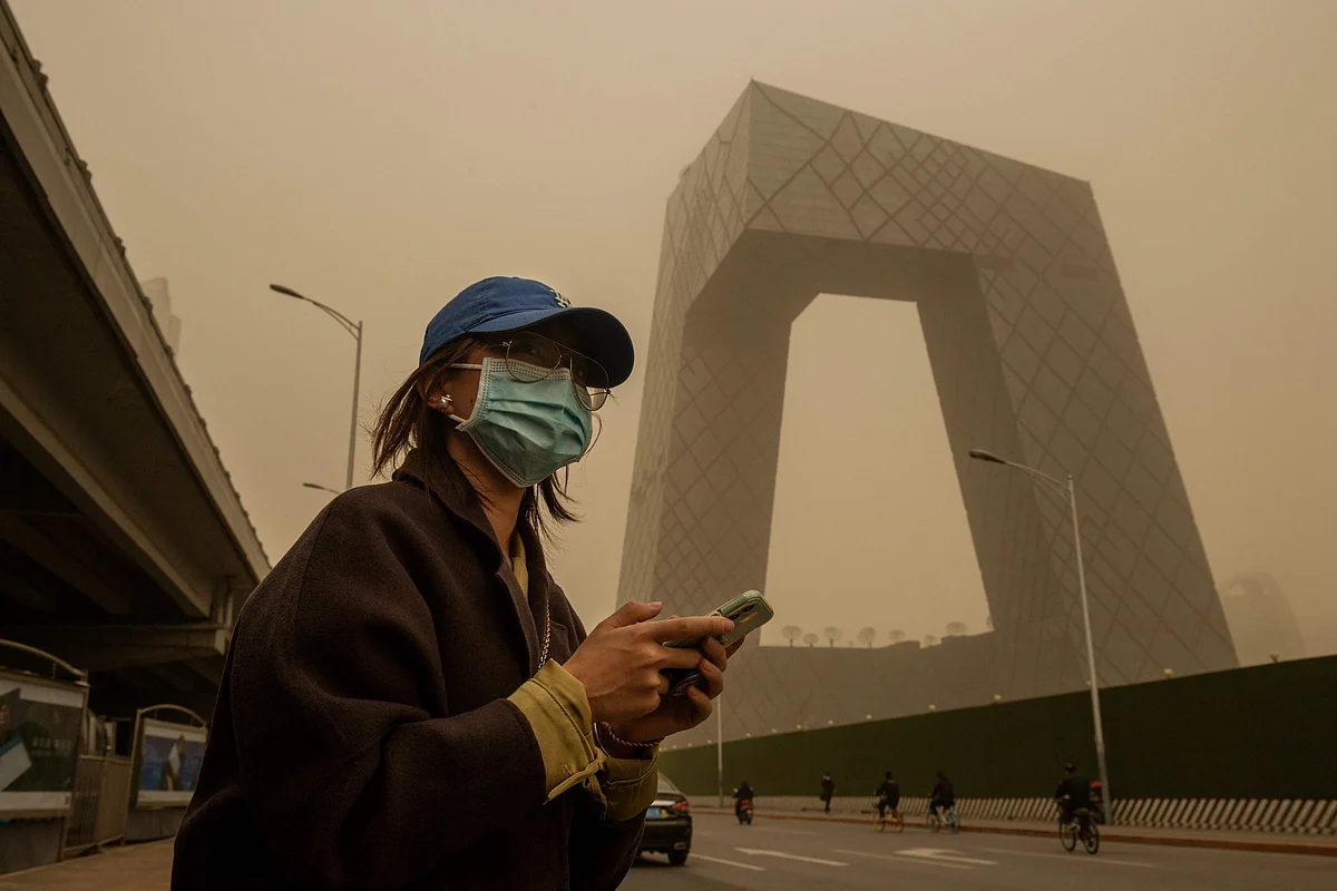 A woman waits at a bus stop during a sandstorm in the financial district in Beijing on March 15, 2021.