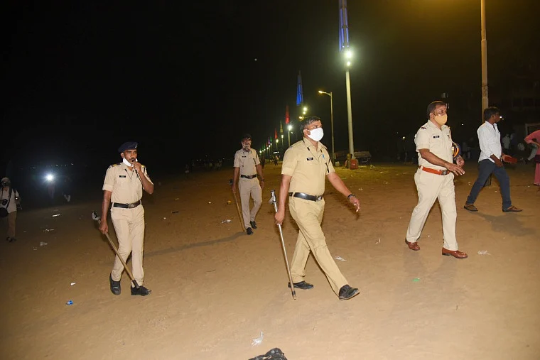 Police personnel conduct a flag march at Juhu Beach during night curfew, imposed by the authorities to curb the spread of coronavirus, in Mumba