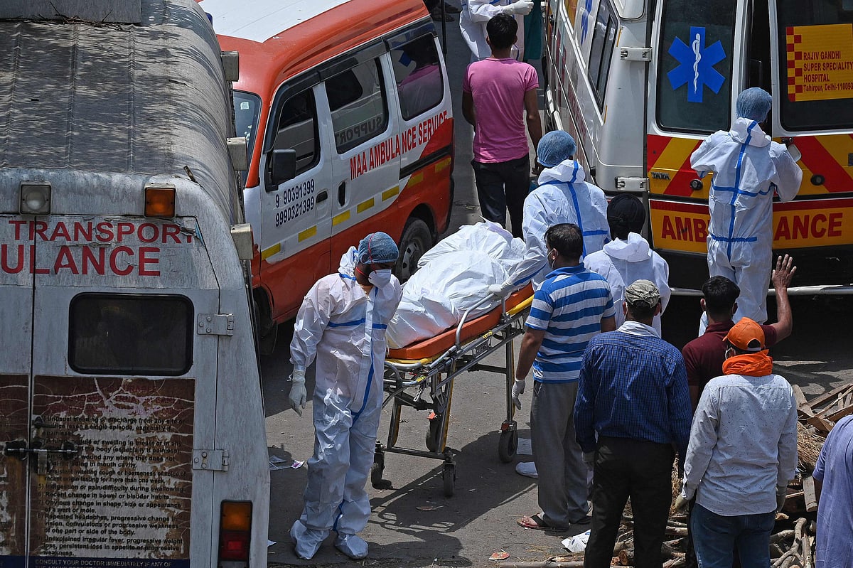 Family members and ambulance workers in PPE kits (Personal Protection Equipment) carry the bodies of victims who died of the Covid-19 coronavirus at a crematorium in New Delhi on April 27, 2021.