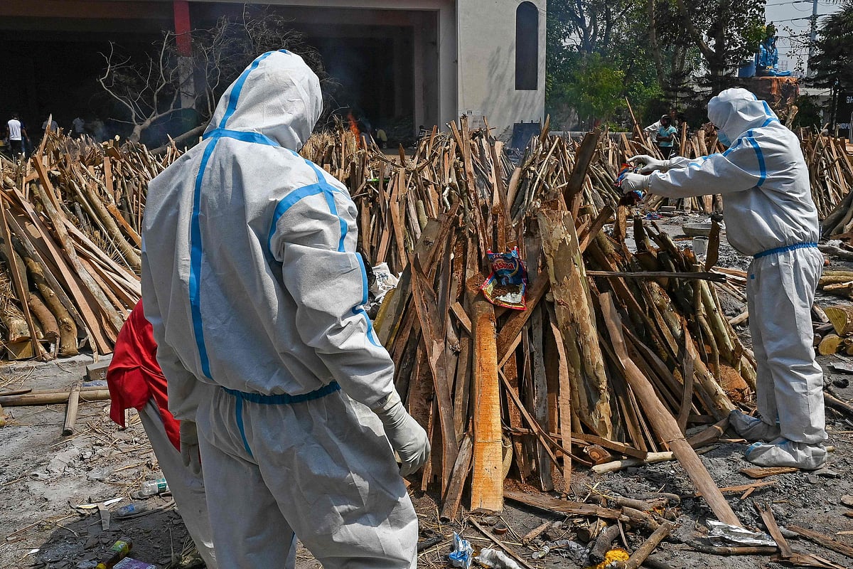 Family members and relatives wearing PPE kits (Personal Protection Equipment) perform the last rites of victims who died of the Covid-19 coronavirus during mass cremation held at a crematorium in New Delhi on April 27, 2021.
