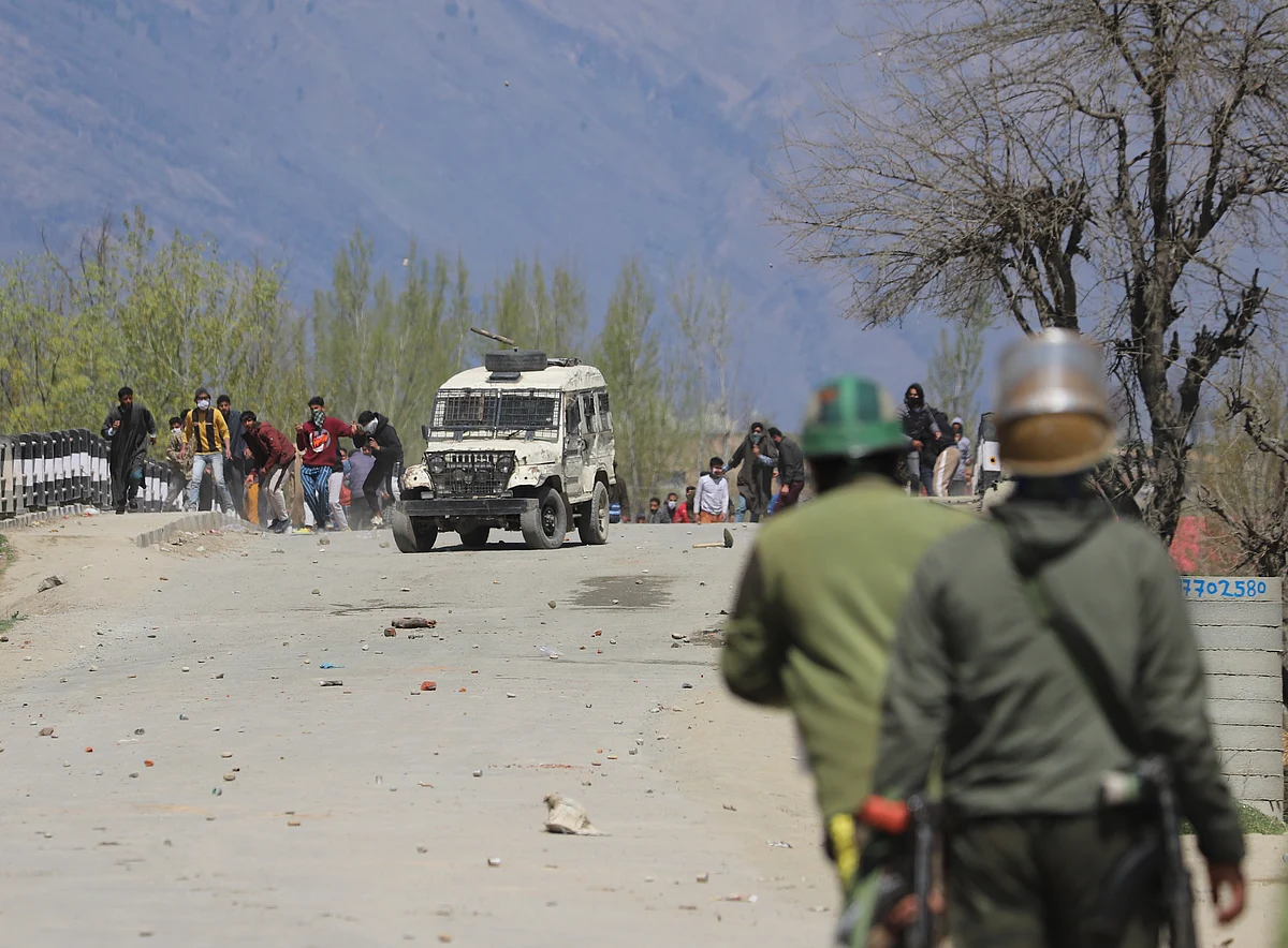 Policemen stand in position as Kashmiri protesters throw stones towards the government forces during the clashes near the site of encounter in Pulwama district of South Kashmir.