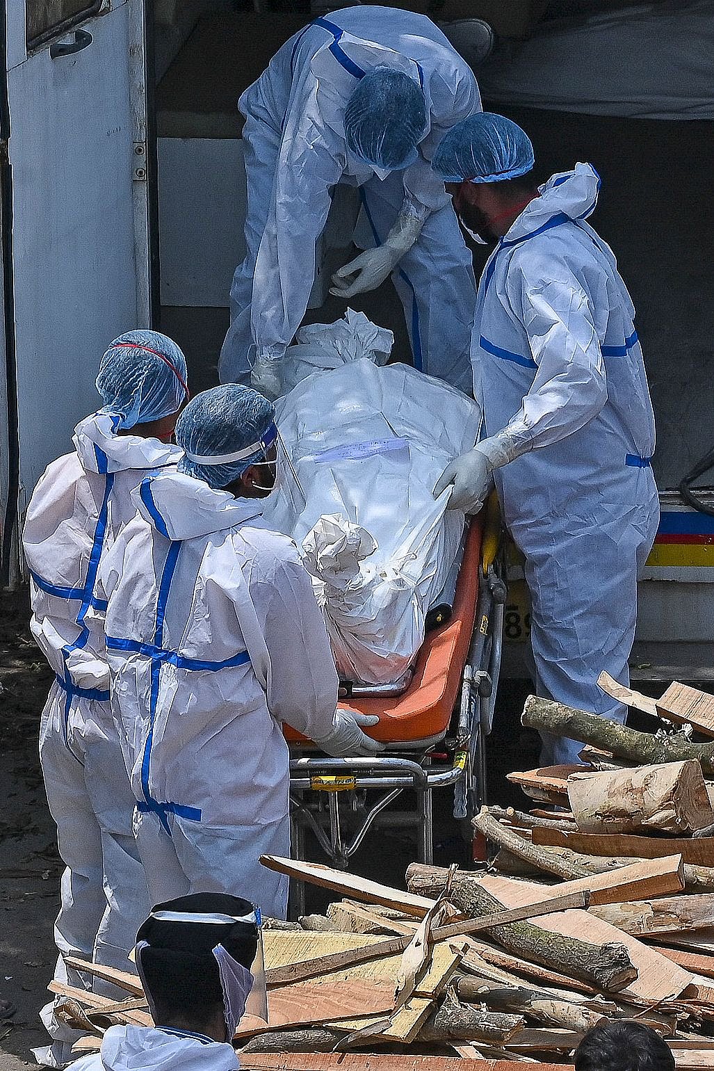 Family members and ambulance workers wearing PPE kits (Personal Protection Equipment) carry the bodies of patients who died of the Covid-19 coronavirus during mass cremation held at a crematorium in New Delhi on April 27, 2021.