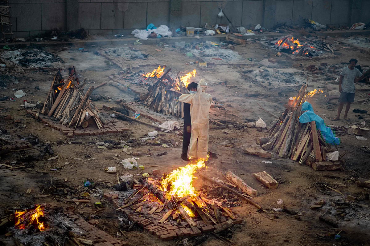 Family members embrace each other amid burning pyres of victims who lost their lives due to the Covid-19 coronavirus at a cremation ground in New Delhi on April 26, 2021.