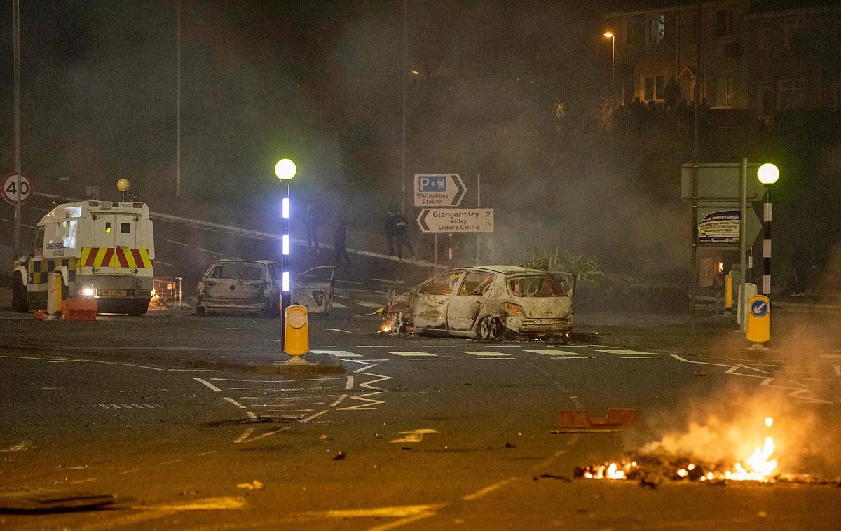 A burnt out car and flames are seen at the scene of violence in Newtownabbey, north of Belfast, in Northern Ireland on April 3, 2021.
