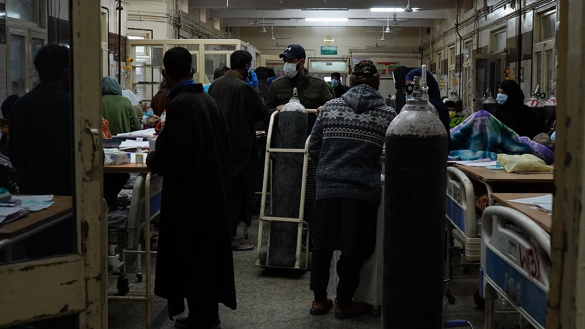 Relatives of COVID-19 patients carry oxygen cylinders to refill at SMHS Hospital in Srinagar, Kashmir. 