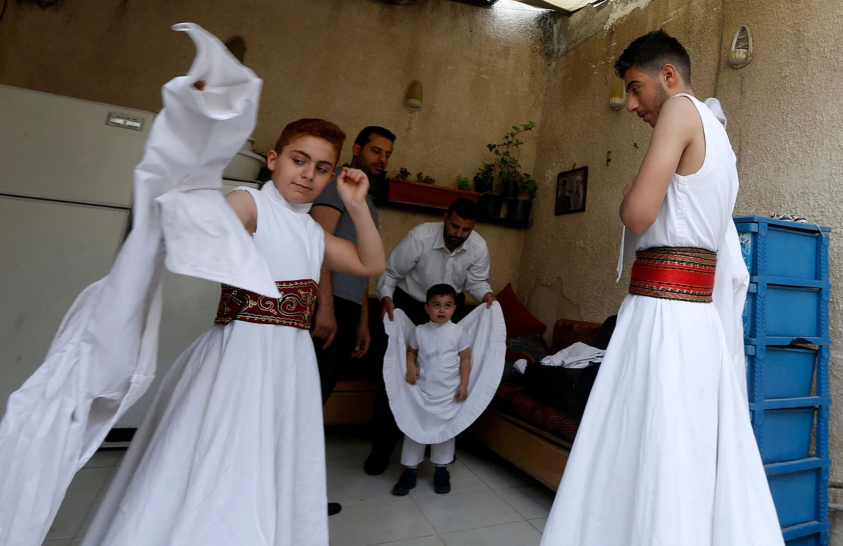 Sufi Dervish dancers of the Kharrat family don their costumes at their home in the Shahgur district of the old city of Syrias capital Damascus on May 6, 2021.
