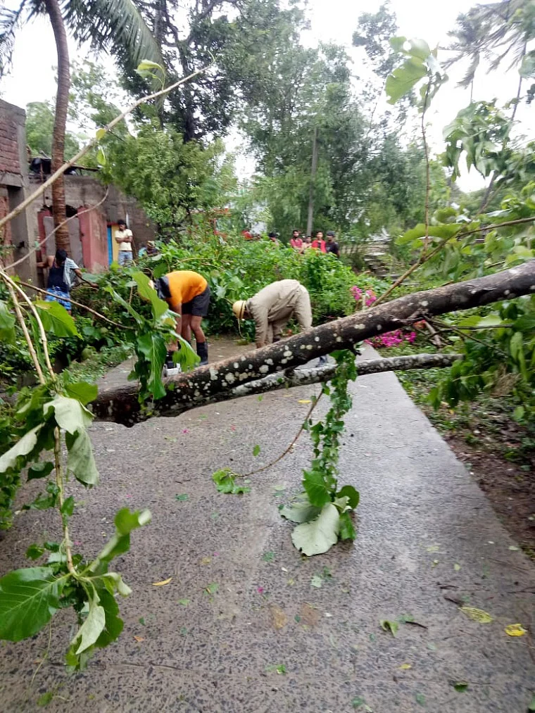 Firefighters personnel clear a fallen tree from a road as they carry out restoration works in the aftermath of Cyclone Yaas