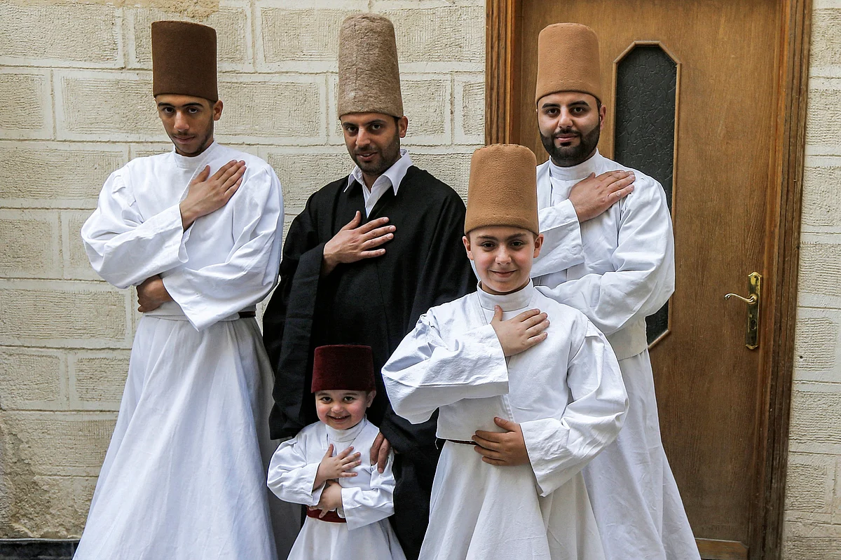 Sufi Dervish dancer Mahmoud al-Kharrat (C top), his brother Muayad (R behind), Muayads son Anas (C below) and other members of the Kharrat family pose for a picture in costume at their home in the Shahgur district of the old city of Syrias capital Damascus on May 6, 2021