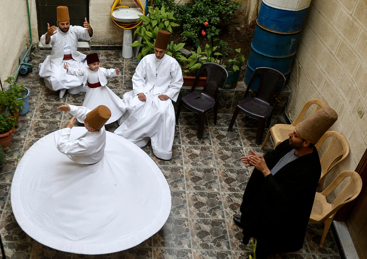 Sufi Dervish dancer Mahmoud al-Kharrat (R), 34, applauds other members of his family as they dance at a courtyard in their house in the Shahgur district of the old city of Syrias capital Damascus on May 6, 2021.