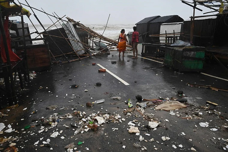 A resident walks amidst debris near stalls in a beachfront area while strong winds batter Balasore district